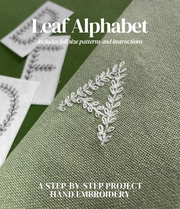 Leaf alphabet embroidery pattern stitched in white thread on green fabric