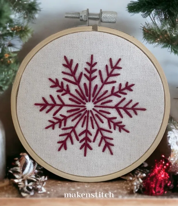 Burgundy snowflake hand embroidery pattern in a hoop