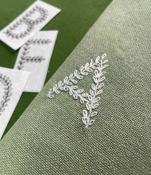 Leaf alphabet hand embroidery with botanical letter A on green fabric