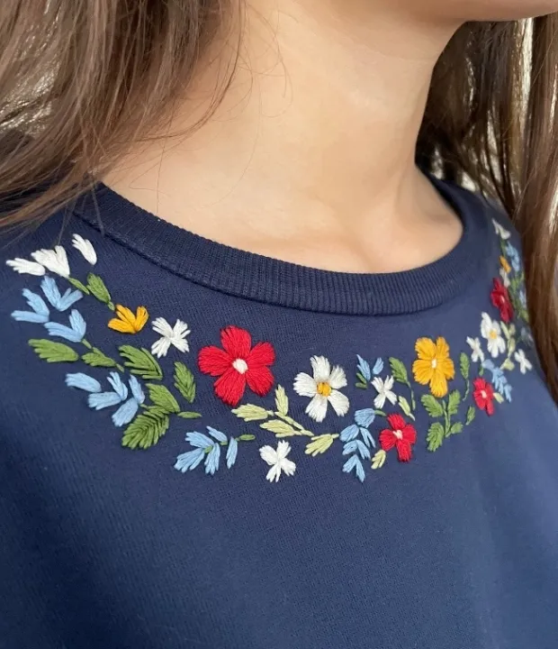 Floral hand embroidery neckline design on a navy blue top